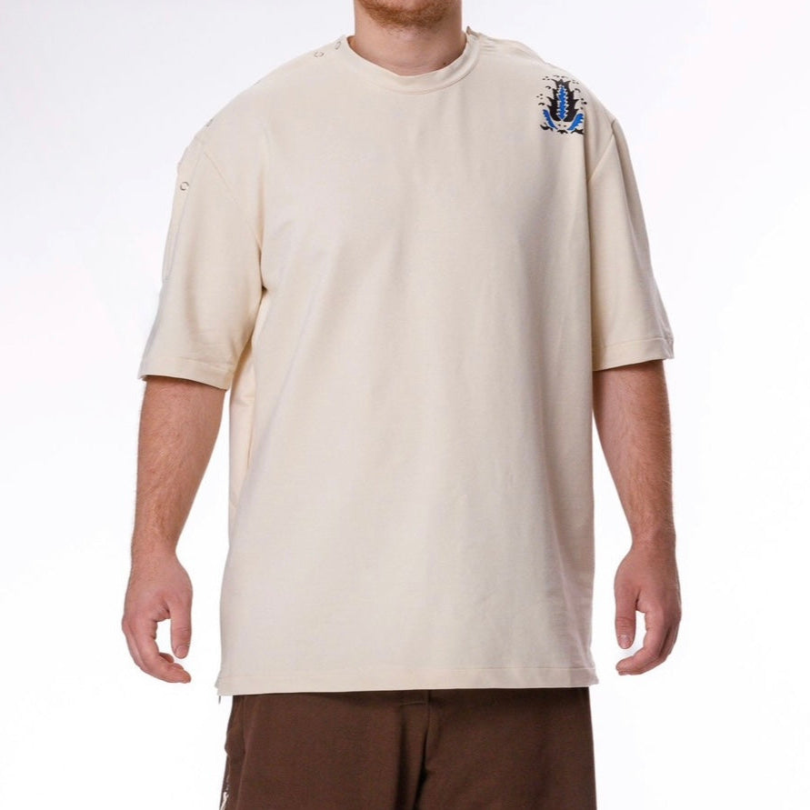 Person wearing a beige t-shirt and brown pants on a white background